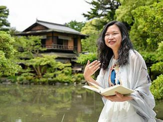 「この街で研究ができてよかった」。京都御苑の一角で古典の愛読書を開いてその魅力を語る、中国人の庄さん（京都市上京区）