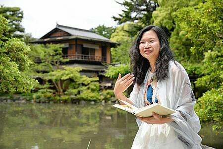 「この街で研究ができてよかった」。京都御苑の一角で古典の愛読書を開いてその魅力を語る、中国人の庄さん（京都市上京区）
